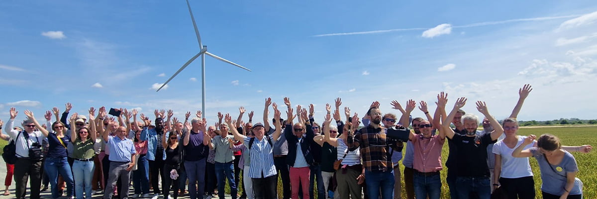 Une foule les bras levés devant une éolienne du parc éolien citoyen d’Andilly-les-Marais