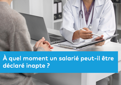 Photographie d’une consultation médicale : un professionnel de santé en blouse blanche assis à un bureau échange avec une personne, prenant des notes sur un dossier ou une tablette.
