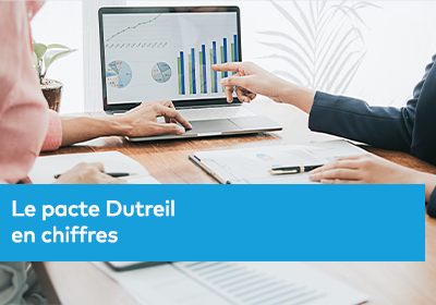 Deux personnes en réunion analysent des graphiques financiers affichés sur un ordinateur portable, avec des documents posés sur une table.