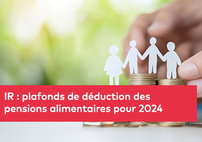 Quatre figurines en papier représentant une famille sont posées sur des piles de pièces de monnaie, avec une main tenant la dernière figurine sur la droite. En arrière-plan, un décor flou et naturel.