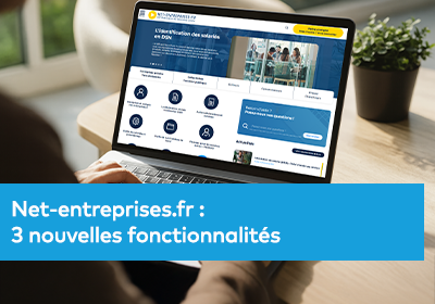 Une personne utilise un ordinateur portable affichant le site web de Net-entreprises avec différentes rubriques visibles à l’écran.